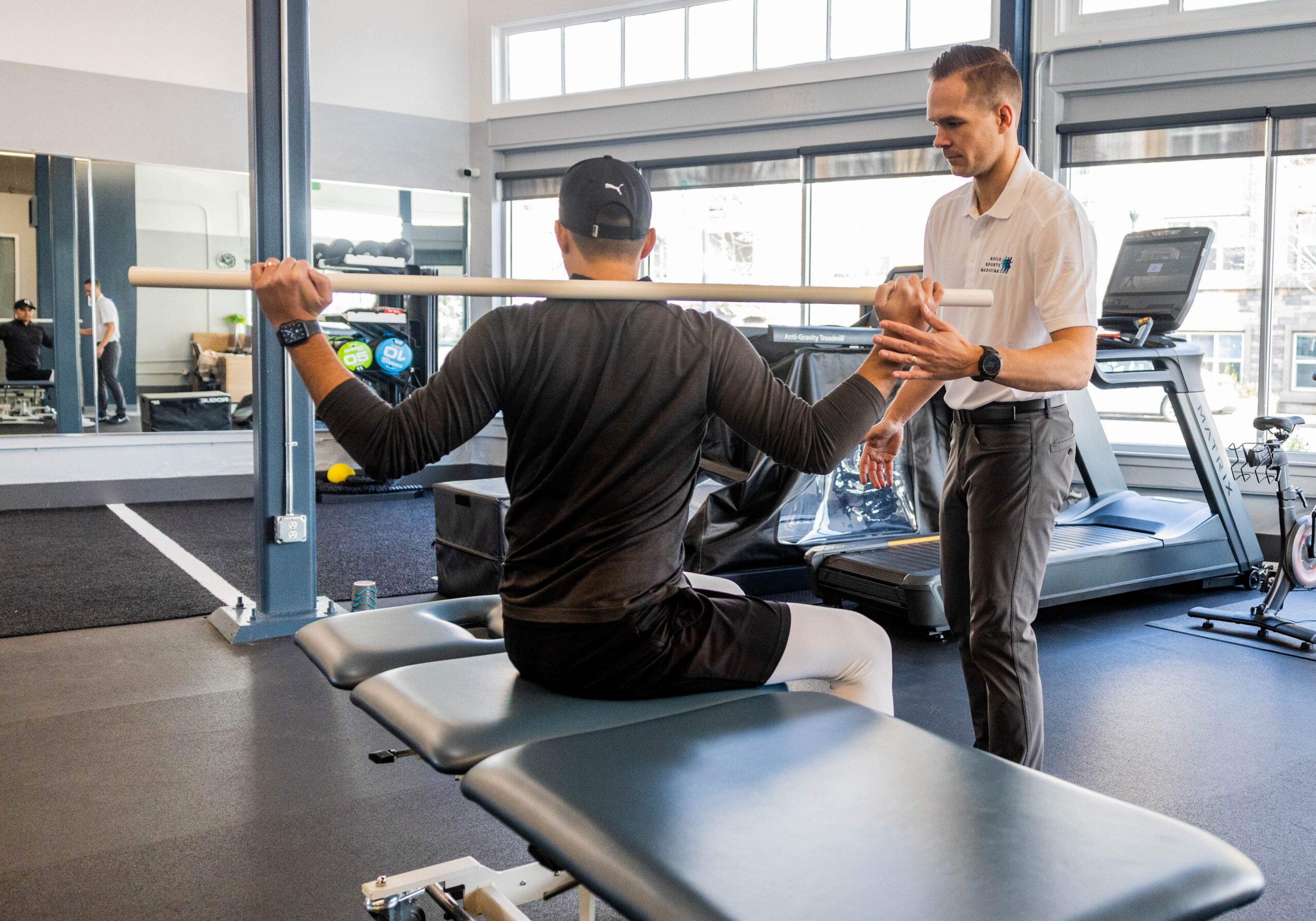 Physical therapist guiding shoulder exercise in clinic gym