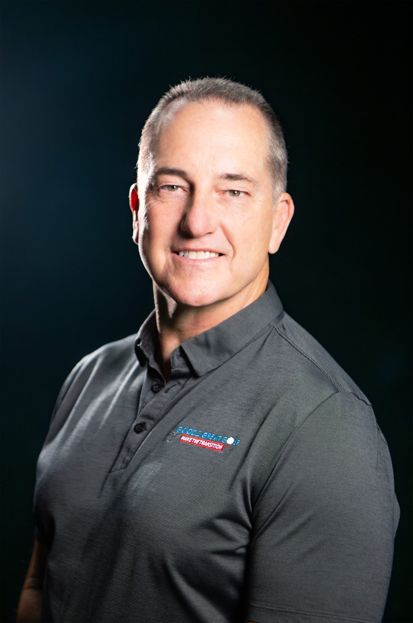 Professional headshot of man in gray polo shirt