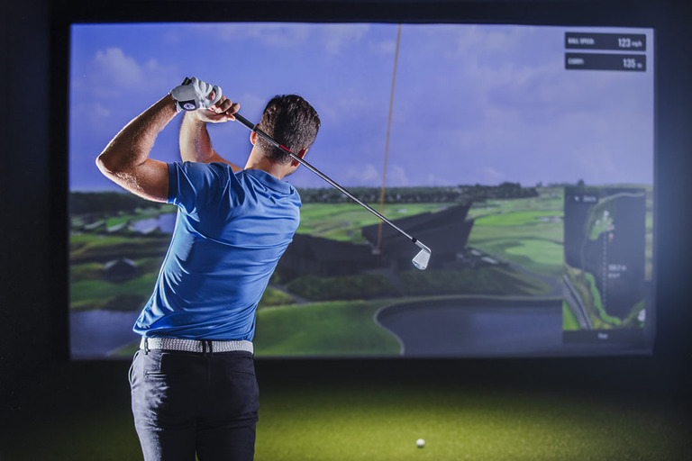 Man playing golf on indoor simulator screen