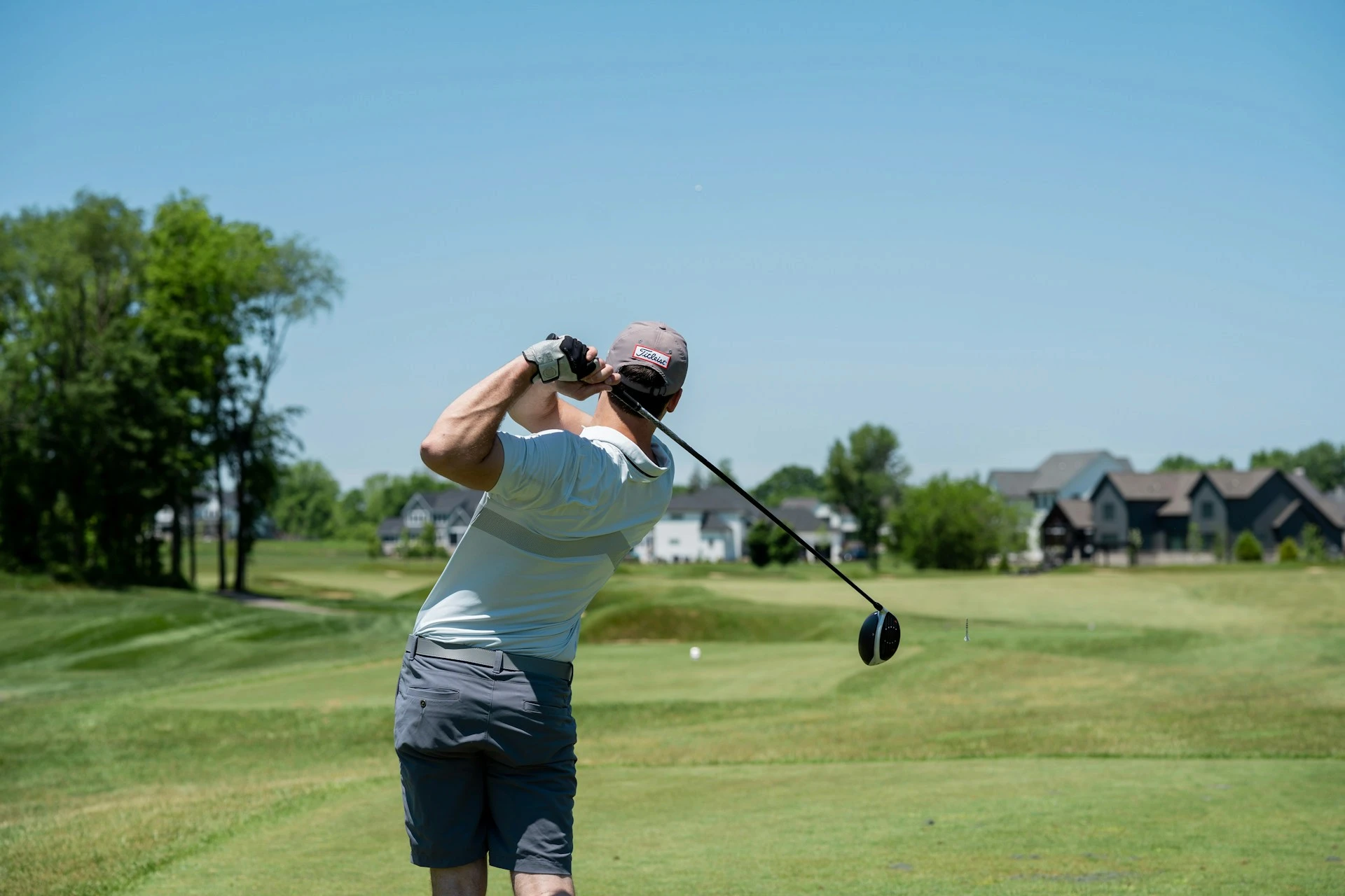 Golfer swinging driver on sunny golf course