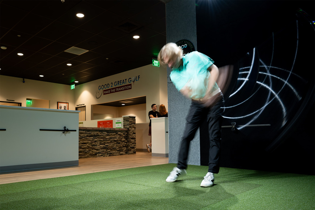 Man swinging golf club in indoor simulator