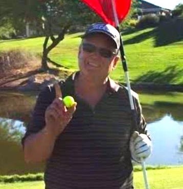 Man holding golf ball and flagstick on course